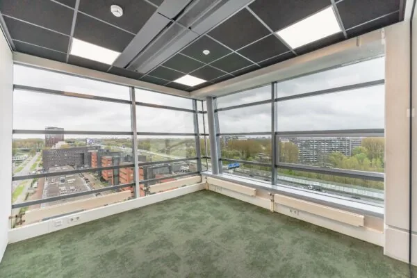 Licht hoekkantoor met grote ramen en uitzicht op de Joop Geesinkweg in Amsterdam.